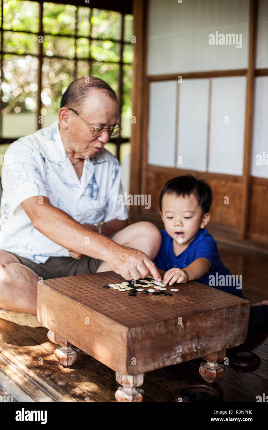 L'homme japonais et petit garçon assis sur le plancher sur porche de maison japonaise traditionnelle, à l'aller. Banque D'Images