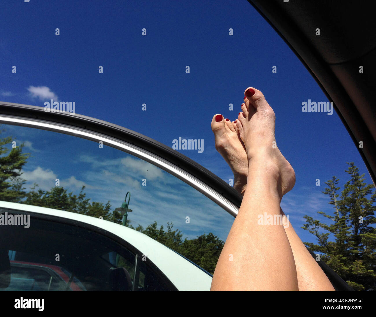 Les jambes de la femme appuyée contre la fenêtre d'une voiture Banque D'Images