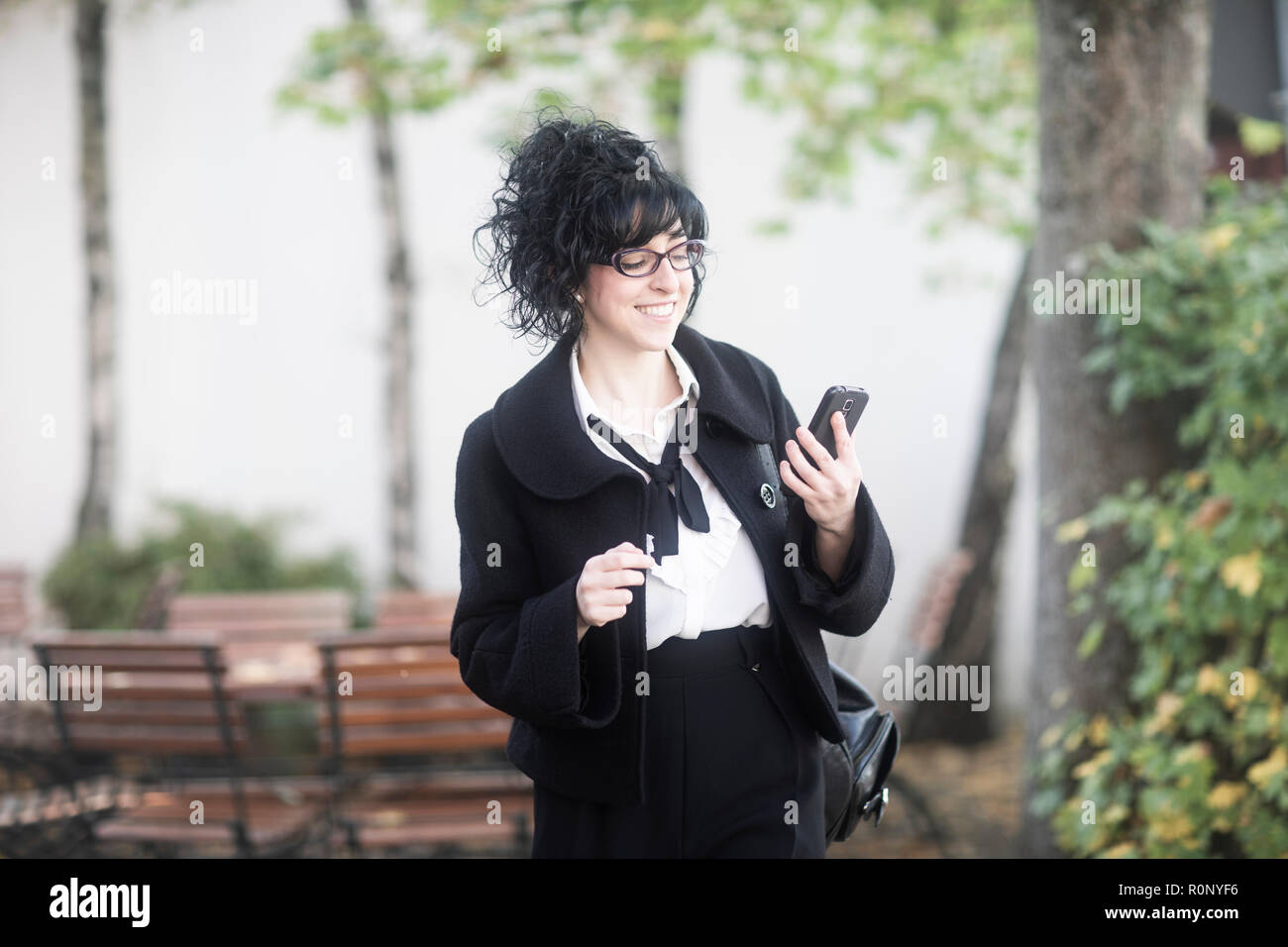 Smiling woman standing outdoors en utilisant son téléphone mobile, Allemagne Banque D'Images