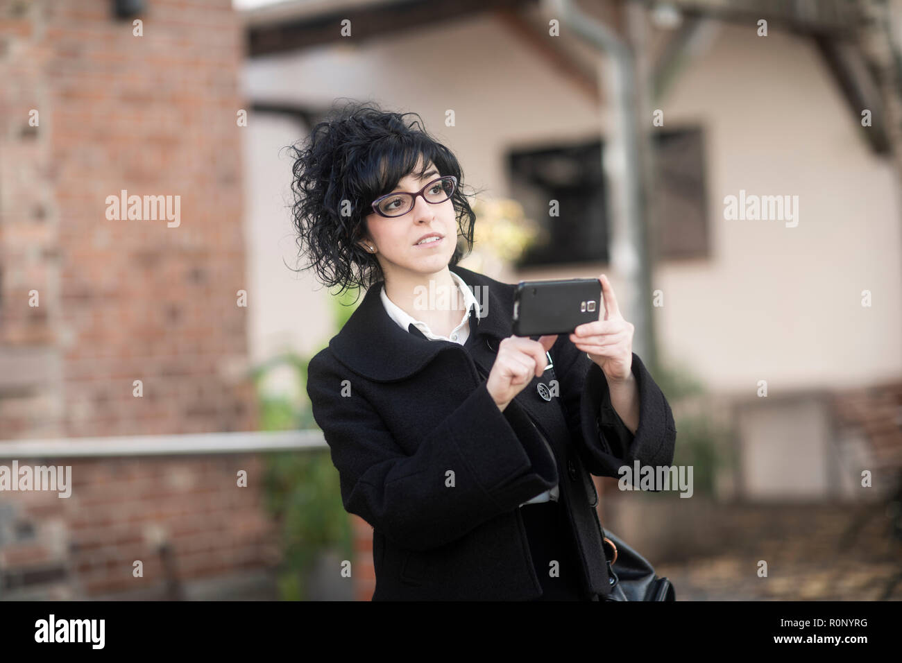 Femme debout à l'extérieur de la prise d'une photo avec son téléphone mobile, Allemagne Banque D'Images