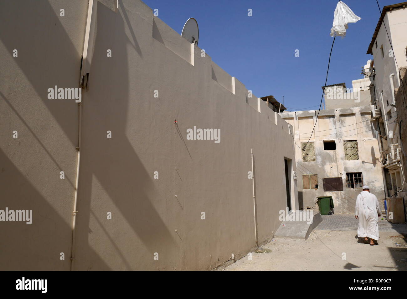 Un homme portant une dishdasha promenades le long d'une allée à l'extérieur de la maison rénové Dar Al Muharraq, Bahrain Pearl Trail, Muharraq, Royaume de Bahreïn Banque D'Images