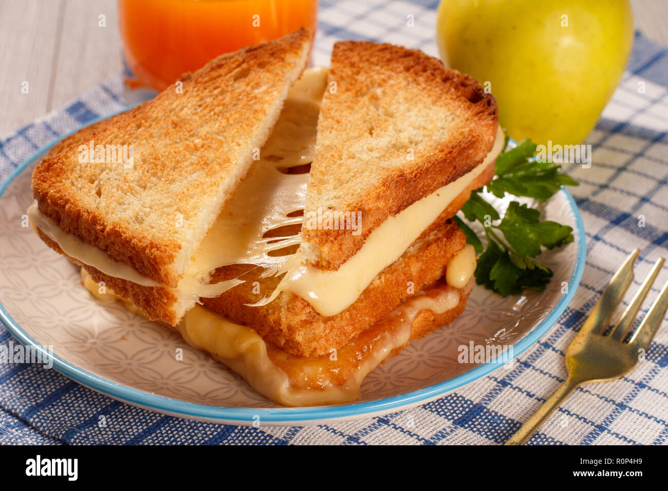 Tranches de pain grillé avec du fromage et persil vert sur plaque blanche, verre de jus d'orange et de pomme verte avec une serviette de cuisine bleu. De la bonne nourriture pour br Banque D'Images