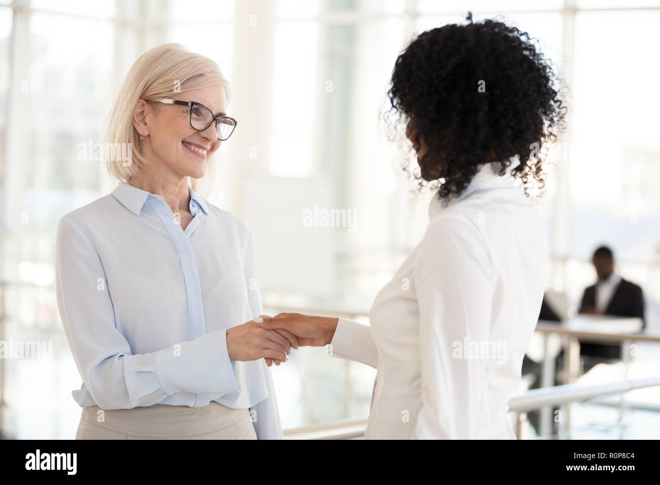 Smiling divers collègues de sexe féminin dans le couloir réunion handshake Banque D'Images
