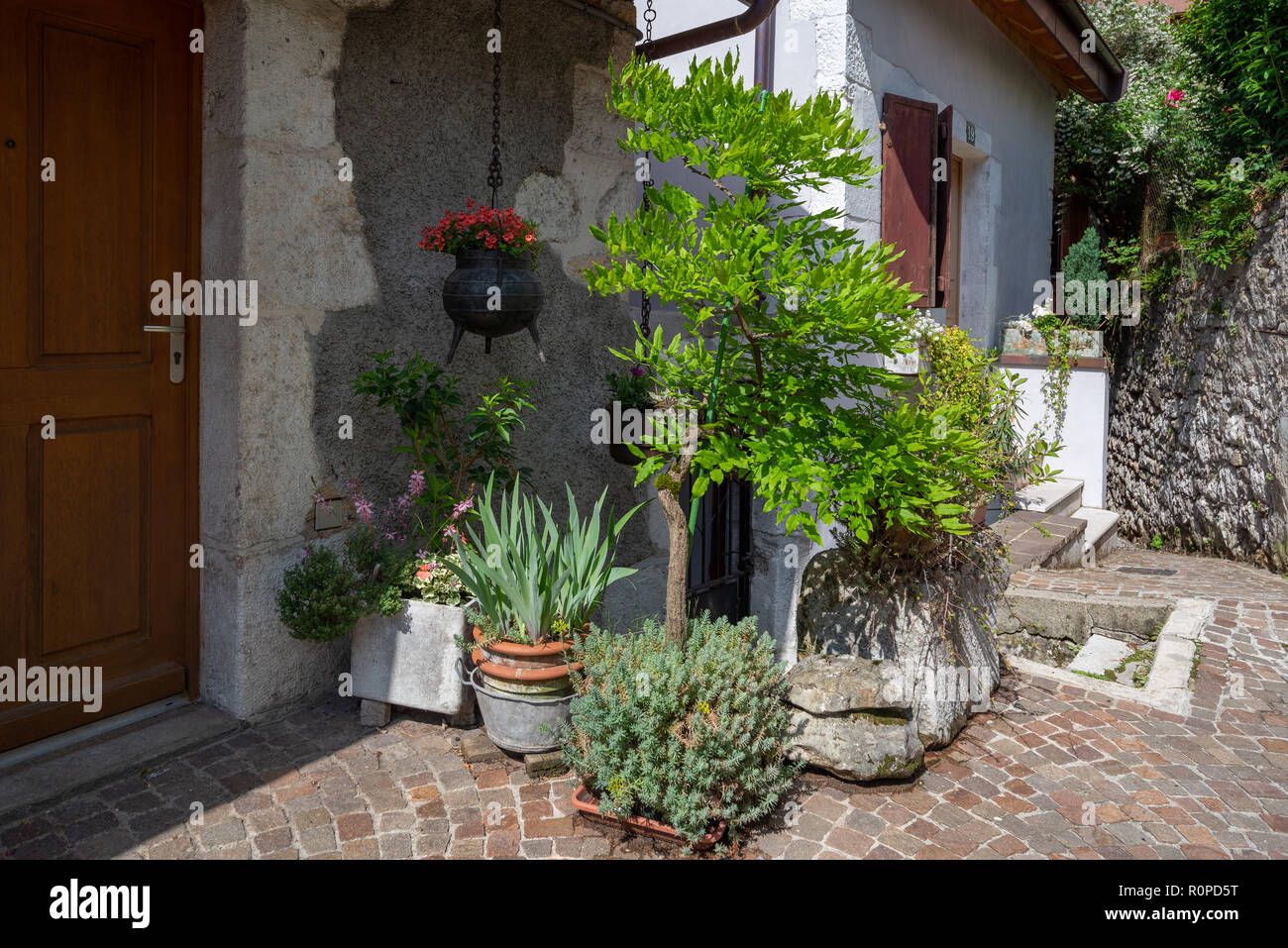 Entrée d'une maison en pierre décorée avec des jardinières et des seaux en fer suspendu un très beau front de rue à Annecy, France Banque D'Images