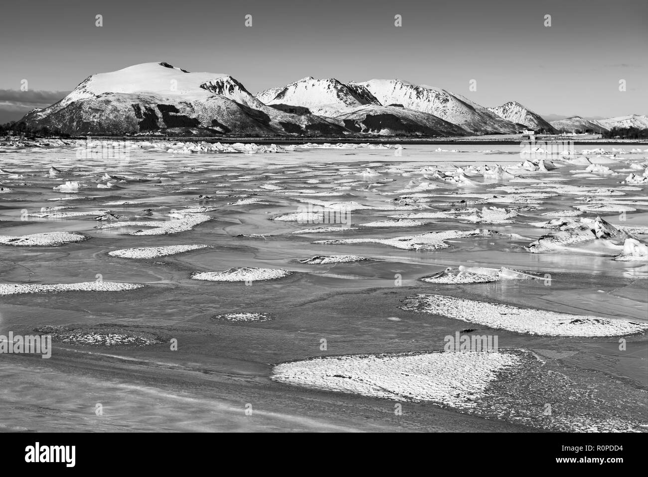 Vue sur lac gelé d'hiver magnifique avec les montagnes enneigées à îles Lofoten, dans le Nord de la Norvège. Arrière-plan de saison. Noir et blanc. Banque D'Images