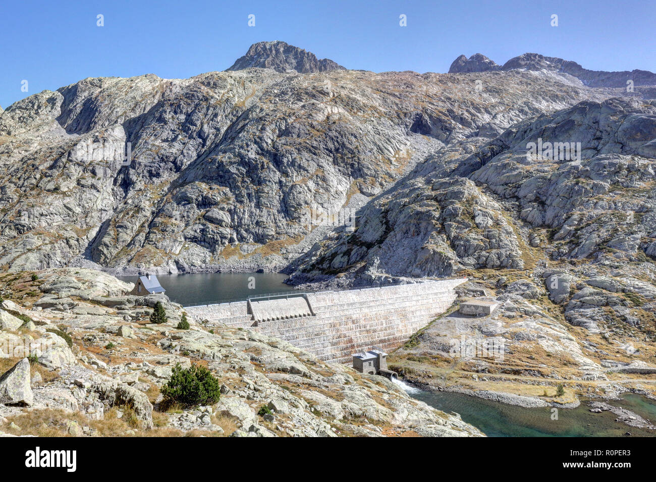 La partie supérieure du lac artificiel Balchimaña avec son barrage, entre les montagnes rocheuses dénudées et un ciel bleu dans une région ensoleillée, en automne, Panticosa Aragon Pyrénées, Espagne Banque D'Images