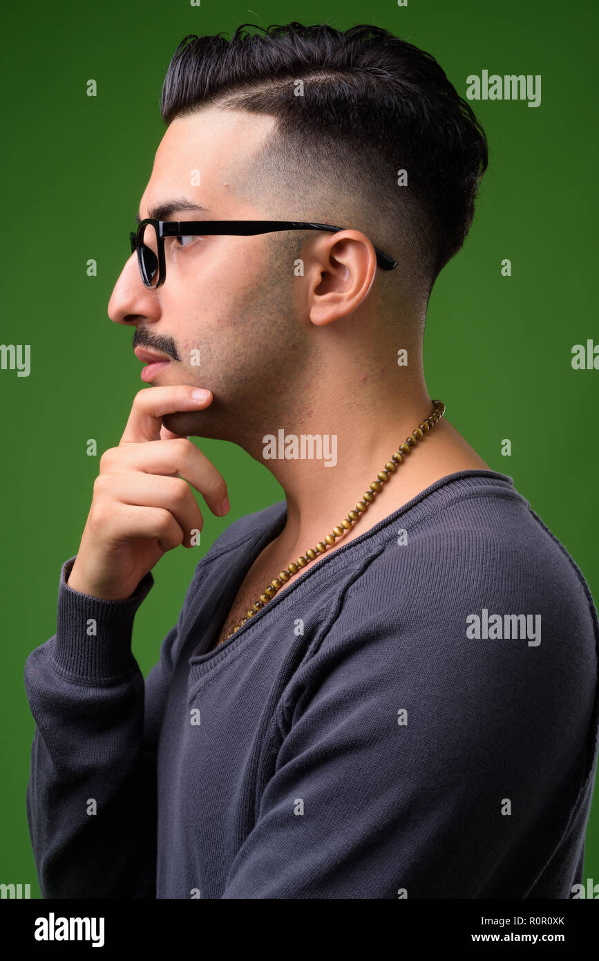 Beau jeune homme iranien avec moustache contre green backgroun Banque D'Images