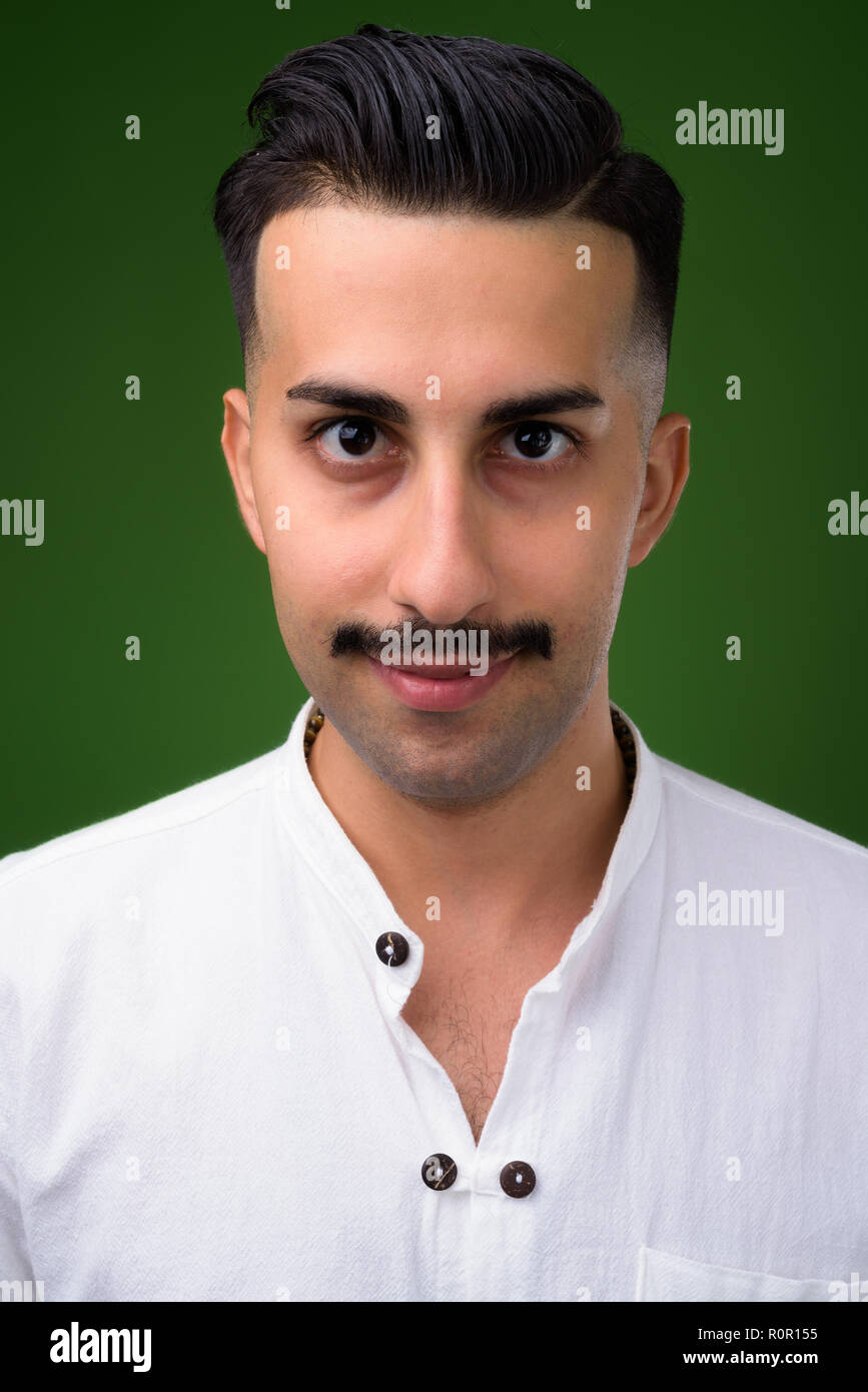 Beau jeune homme iranien avec moustache contre green backgroun Banque D'Images