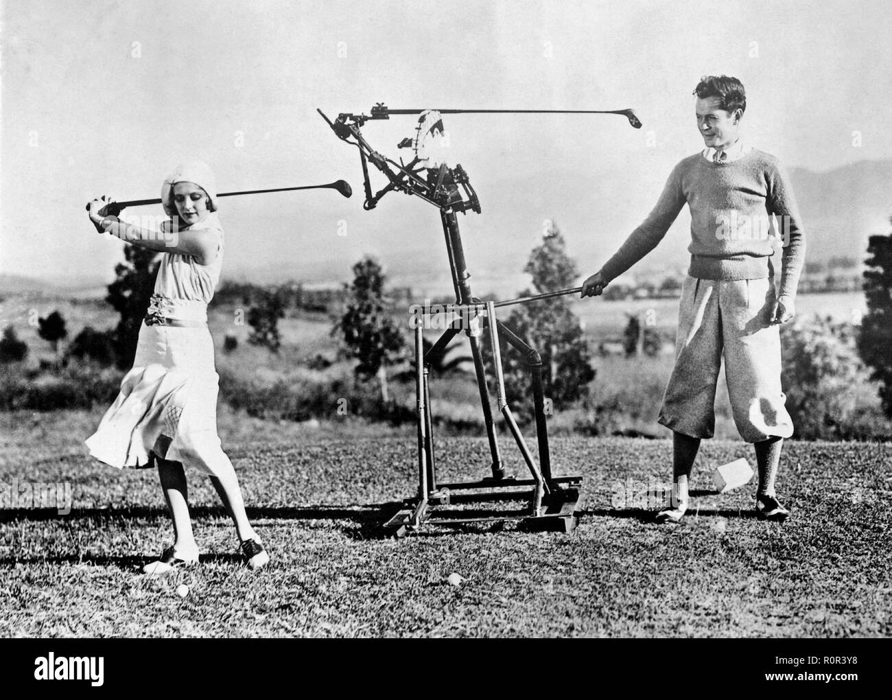 Femme d'apprendre à jouer au golf dans les années 1930. Une jeune femme obtient l'aide d'un instructeur de golf de robot afin de perfectionner son swing. Banque D'Images