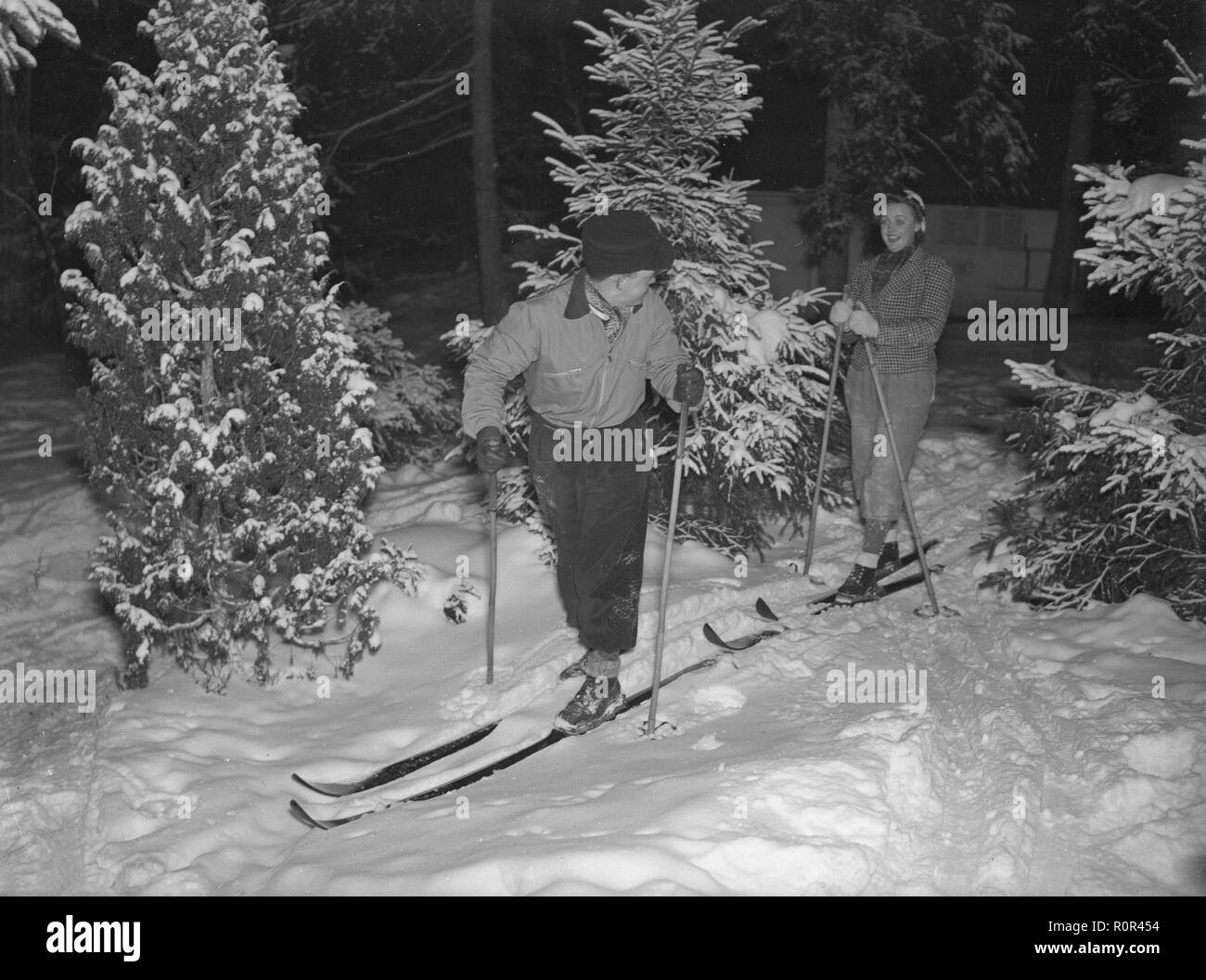 L'hiver dans les années 40. Un jeune couple sont le ski entre les arbres. Suède 1940. Kristoffersson Photo ref 118-8 Banque D'Images