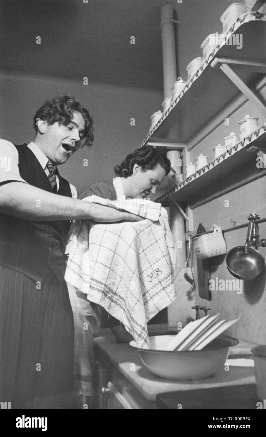 Dans la cuisine des années 40. Le chanteur d'opéra suédois Erik Söderström, 1911-1972 avec son épouse. Sur la photo dans la cuisine les plats de séchage. Suède 1940 Banque D'Images