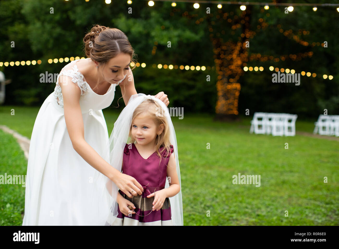 Belle jeune mariée mettre voile blanche de petite fille charmante debout dans le jardin vert Banque D'Images
