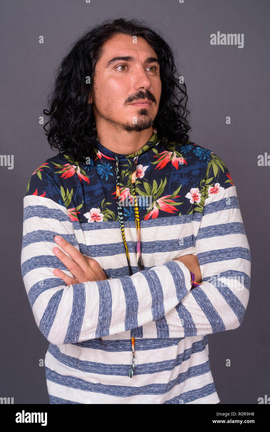 Bel homme avec des cheveux bouclés et d'une moustache contre gray backgroun Banque D'Images