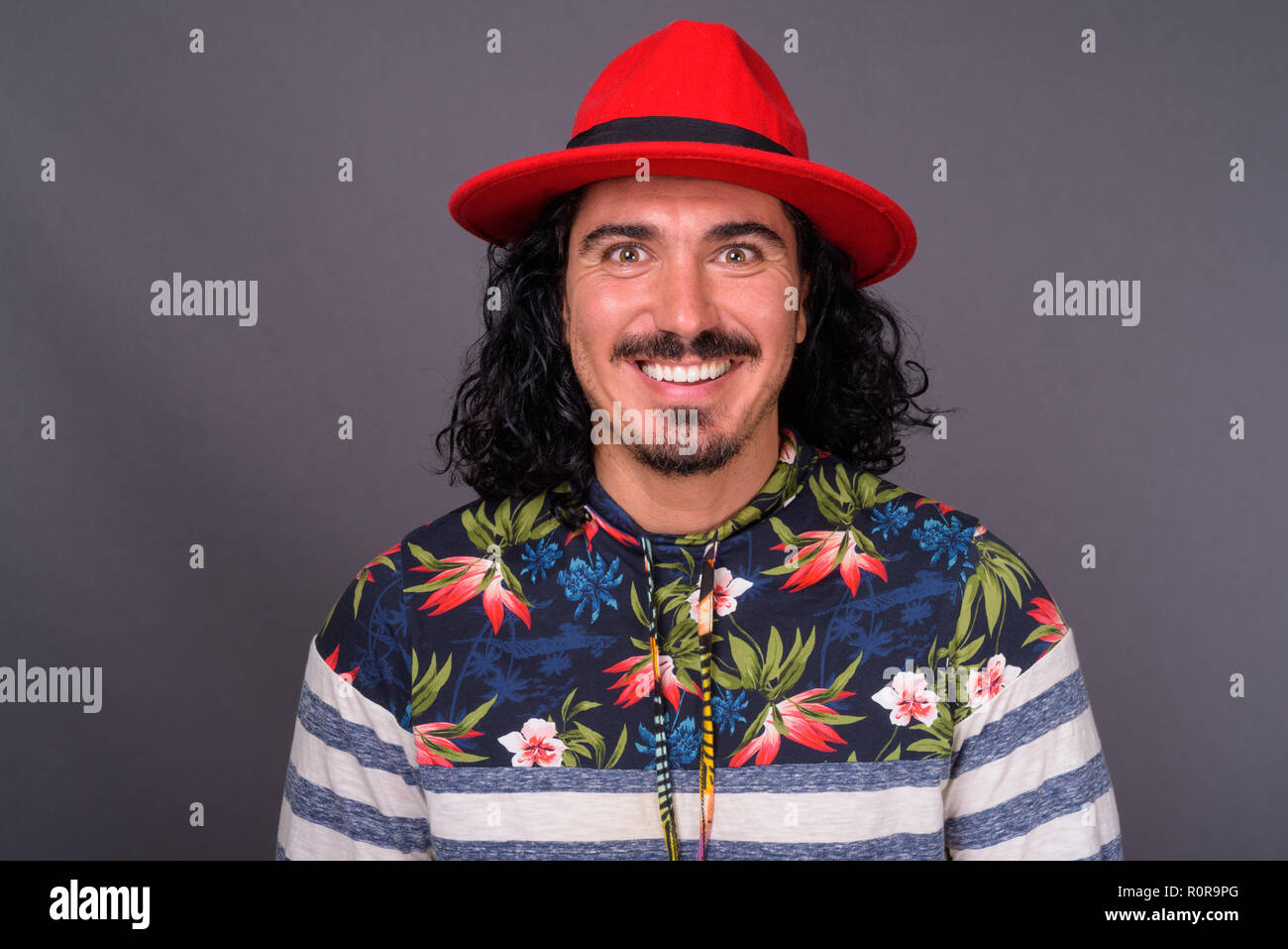 Bel homme avec des cheveux bouclés et d'une moustache contre gray backgroun Banque D'Images