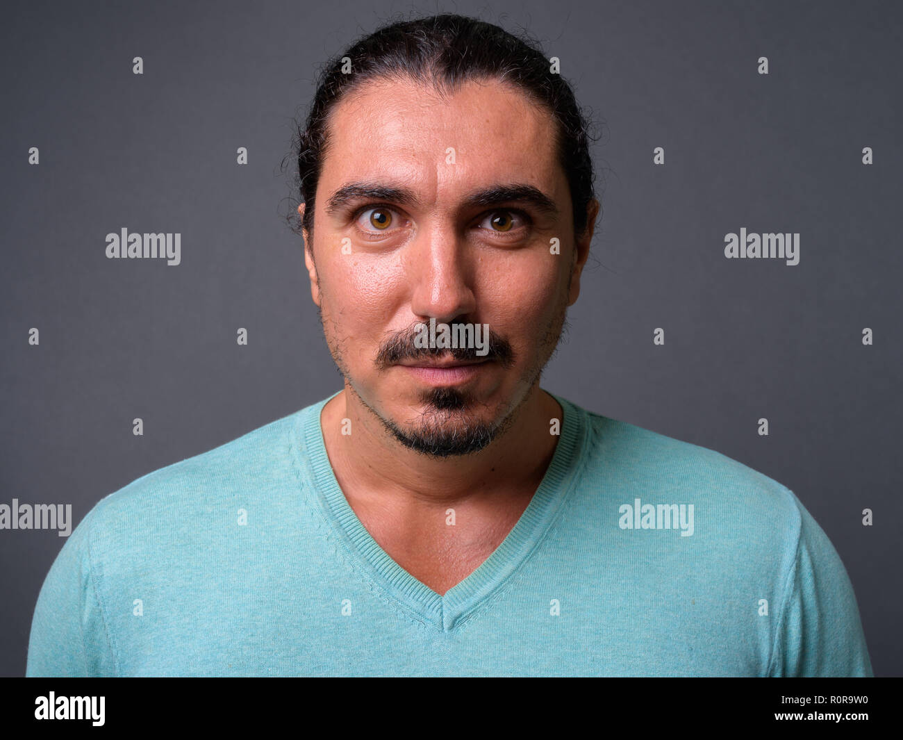 Bel homme avec des cheveux bouclés et d'une moustache contre gray backgroun Banque D'Images