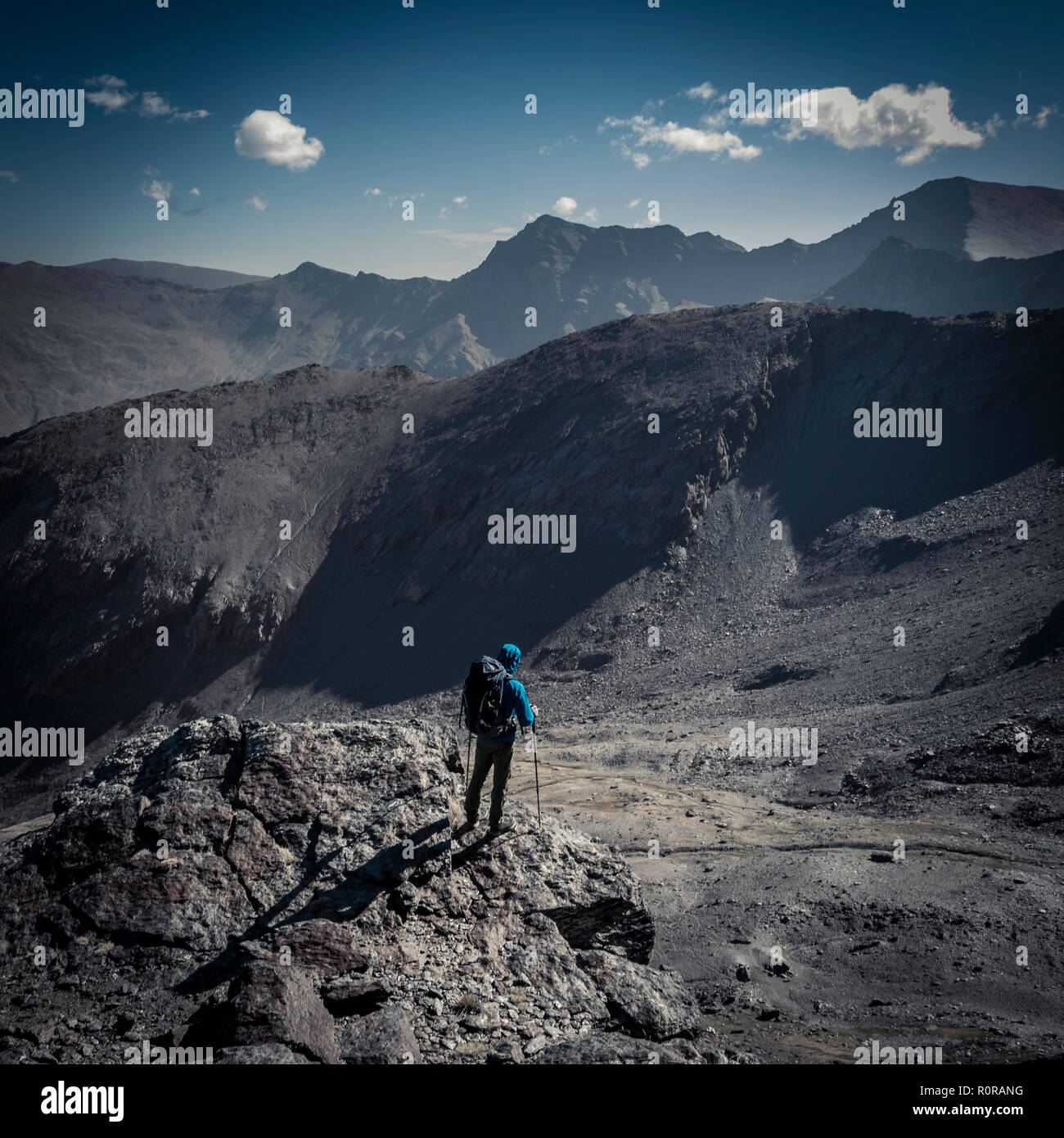 Vue latérale du méconnaissable d'alpiniste avec sac à dos, debout sur la falaise et regarder les montagnes magnifiques aux beaux jours Banque D'Images