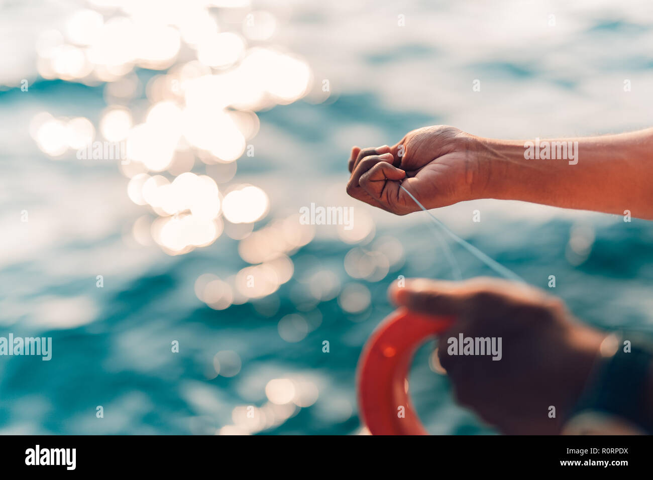 Bien utilisé la ligne à main et bobine de pêche en mer tropicale. Arrière-plan de la mer trouble. Le sport et les loisirs liés à l'eau contexte Banque D'Images