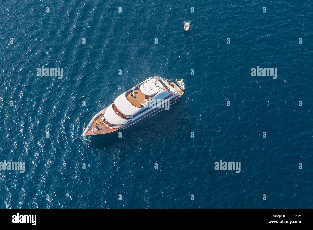 Drone aérien haut bird's eye view photo de yacht de luxe avec terrasse en bois amarré dans les eaux bleu profond de l'île de Mykonos, Cyclades, Grèce Banque D'Images