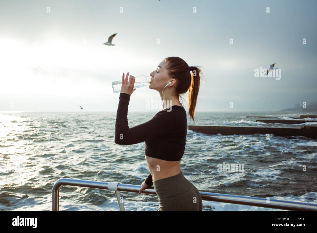 Belle femme athlète remise en forme de l'eau potable au repos après le travail à l'exercice sur la plage Banque D'Images
