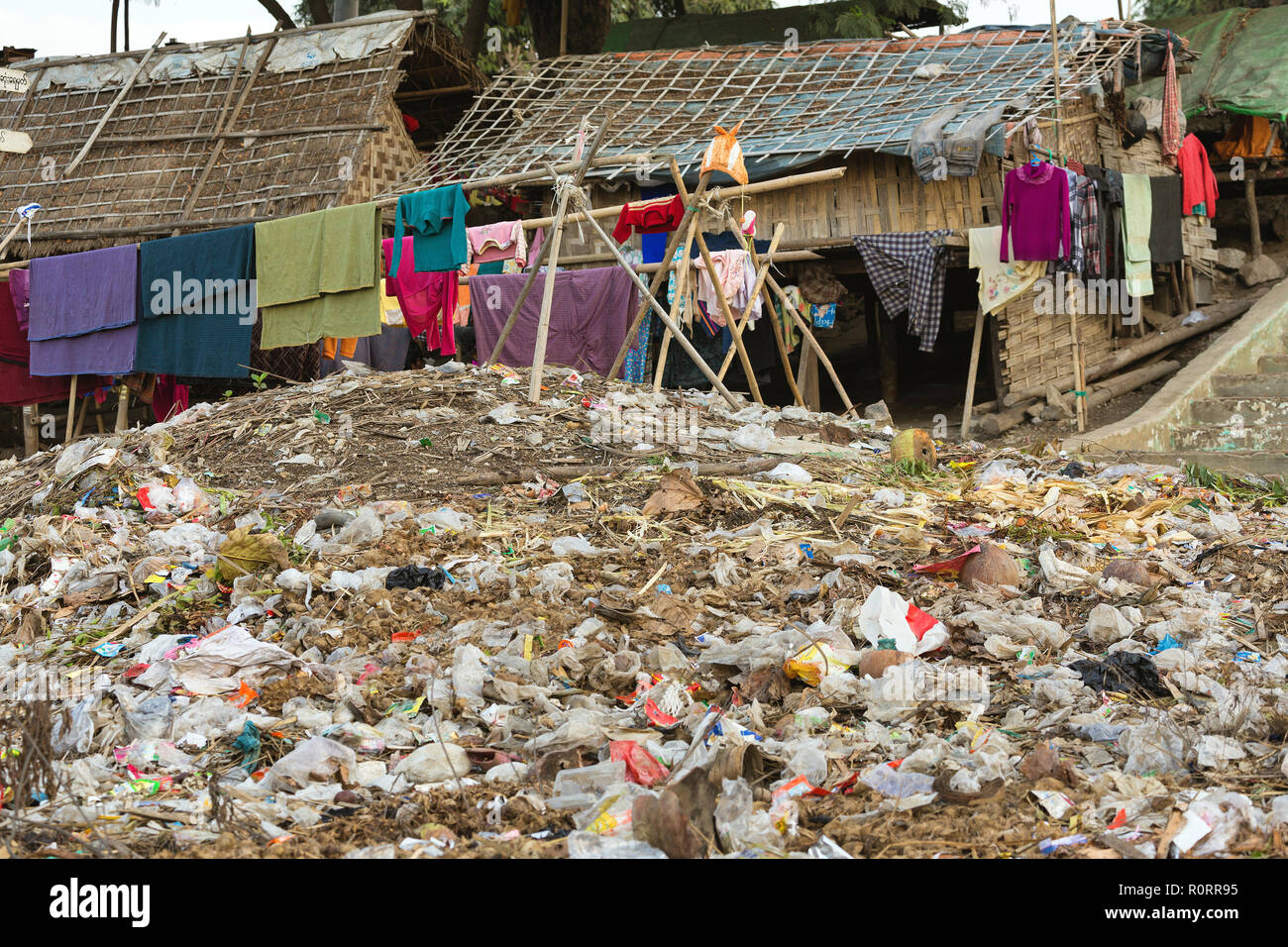 Blanchisserie séchage sous un gros tas de déchets dans un bidonville à Mandalay, Myanmar Banque D'Images
