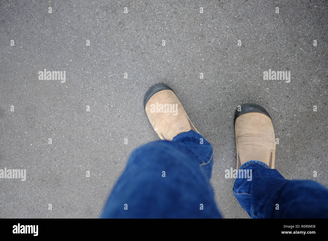 Chaussures en daim marron et bleu jeans commencez à marcher sur son chemin de la vie sur la route en béton. Banque D'Images