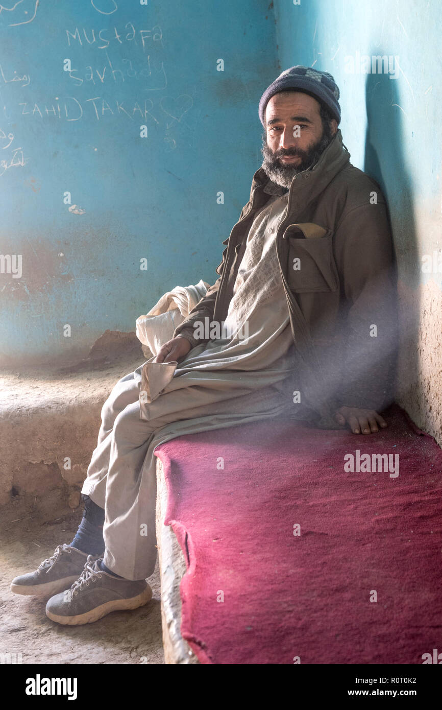 Vieil homme assis sur un banc dans fumeurs Den, ancienne Balkh, Afghanistan Banque D'Images