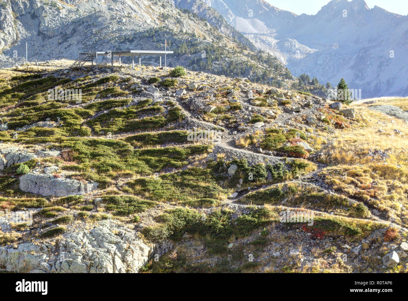 Un chemin en montant une côte à une plate-forme entre les hautes montagnes rocheuses avec de l'herbe jaune et un ciel bleu dans une région ensoleillée, en automne, Panticosa Aragon Pyrénées, Espagne Banque D'Images