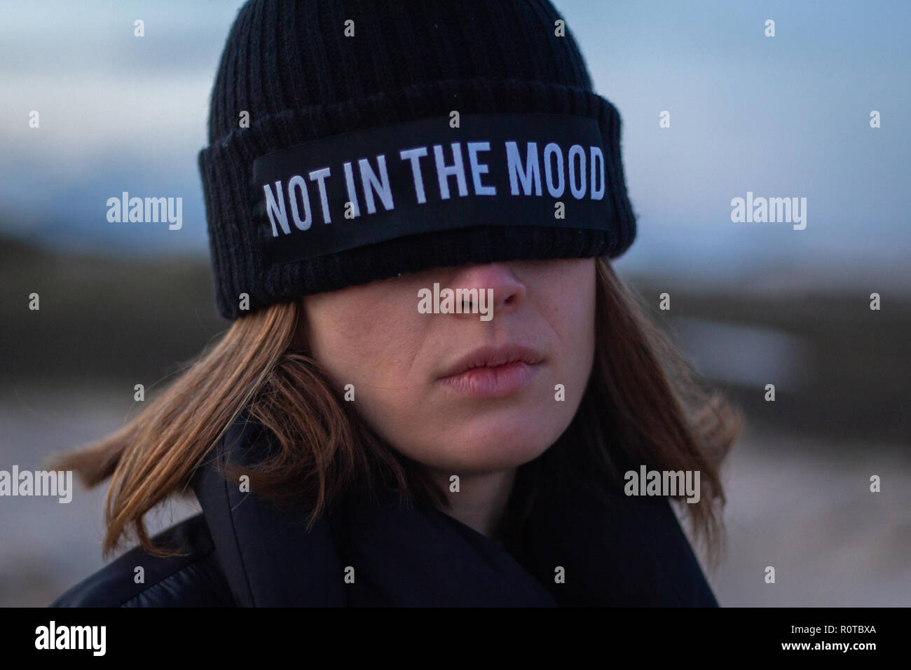 Girl wearing a black cap couvrant ses yeux avec le dit pas dans l'humeur Banque D'Images
