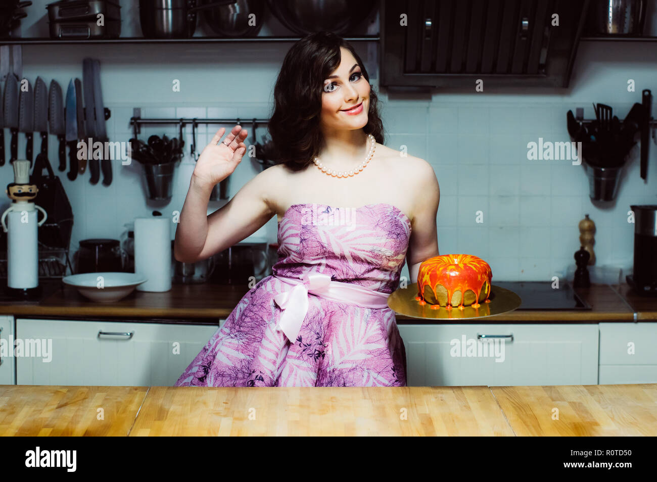 Smiling hostess détient comme de gros gâteau fondant rouge avec anneau Banque D'Images