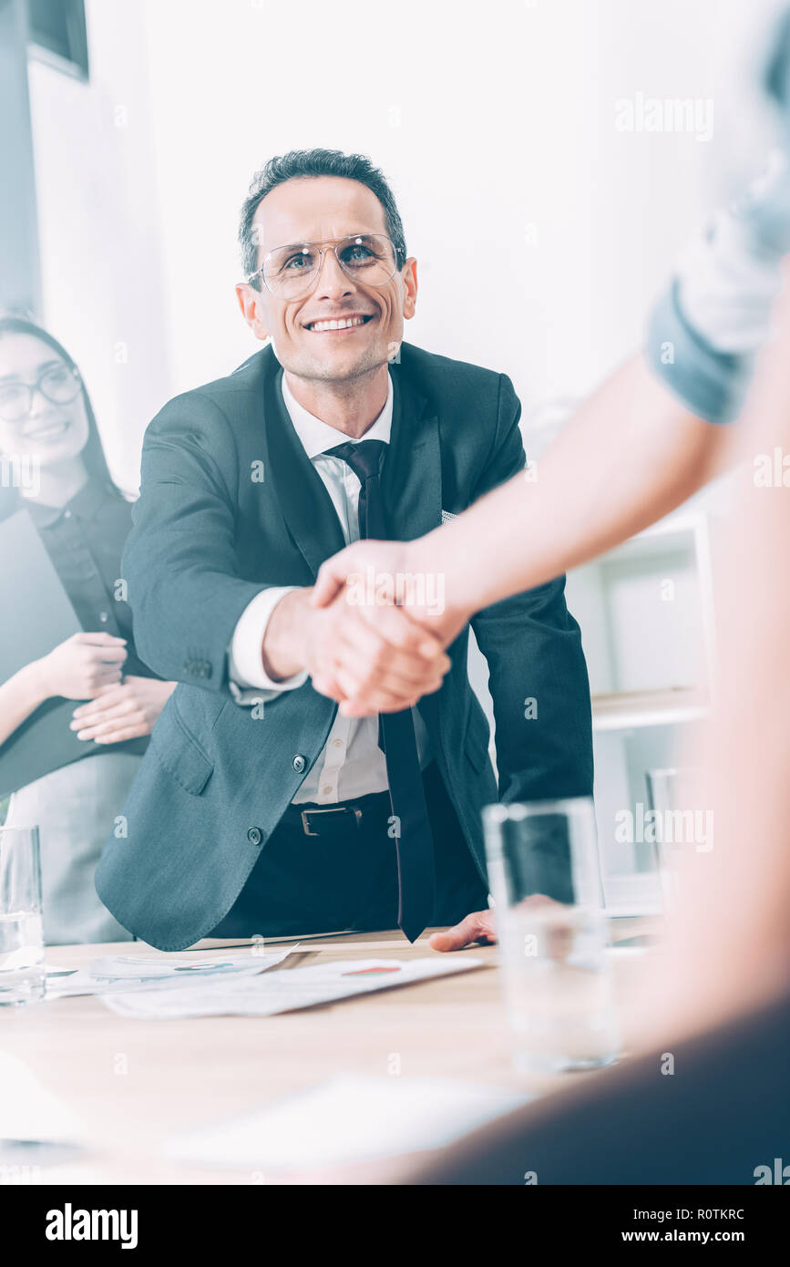 Partenaires d'affaires shaking hands in modern office Banque D'Images