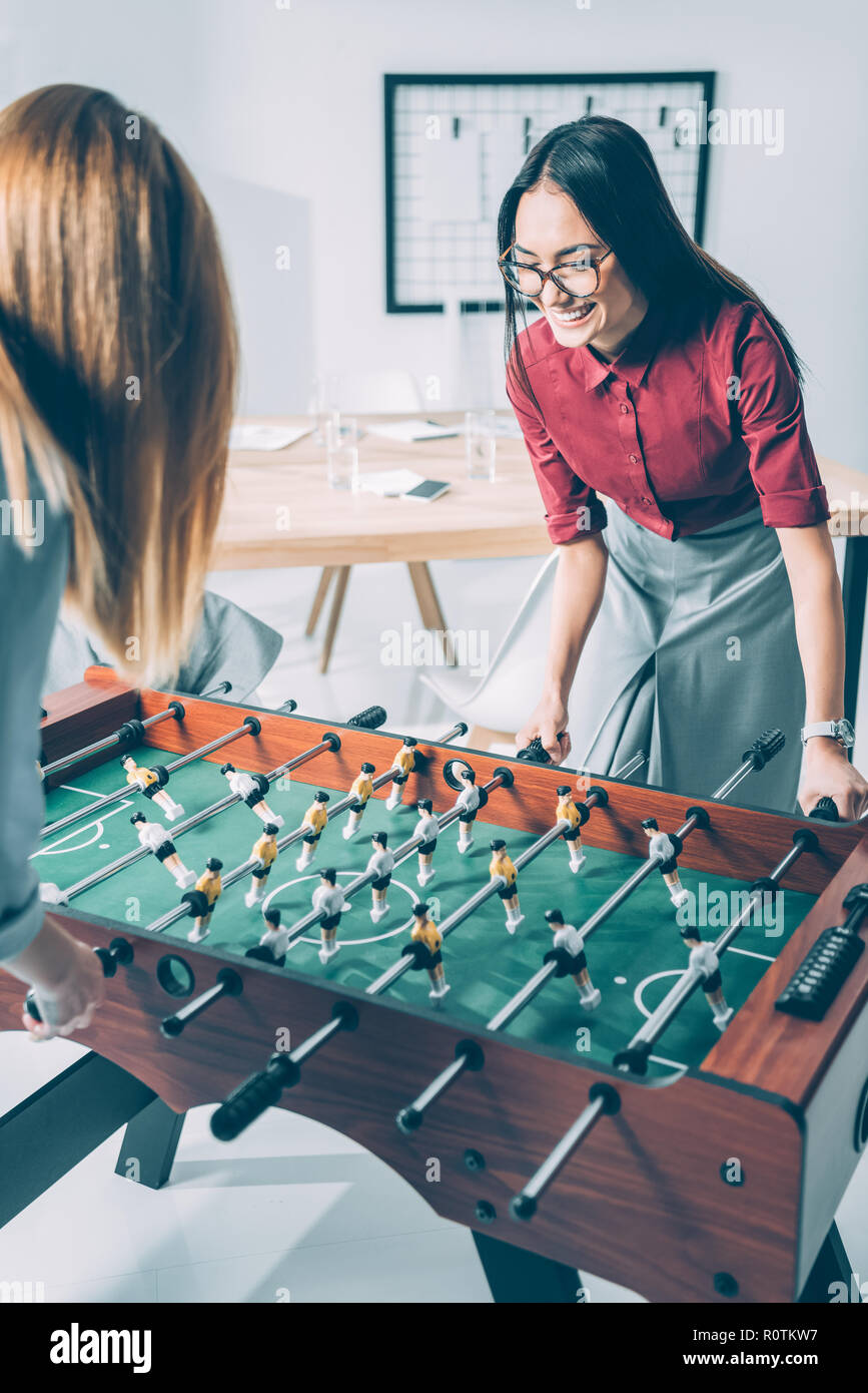 Les jeunes femmes d'attrayants playing table football in modern office Banque D'Images