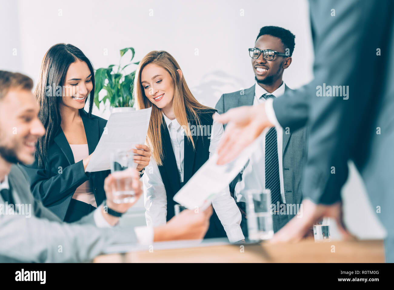 Businesspeople looking at documents pendant que les partenaires ayant multiraciale conversation on foreground Banque D'Images