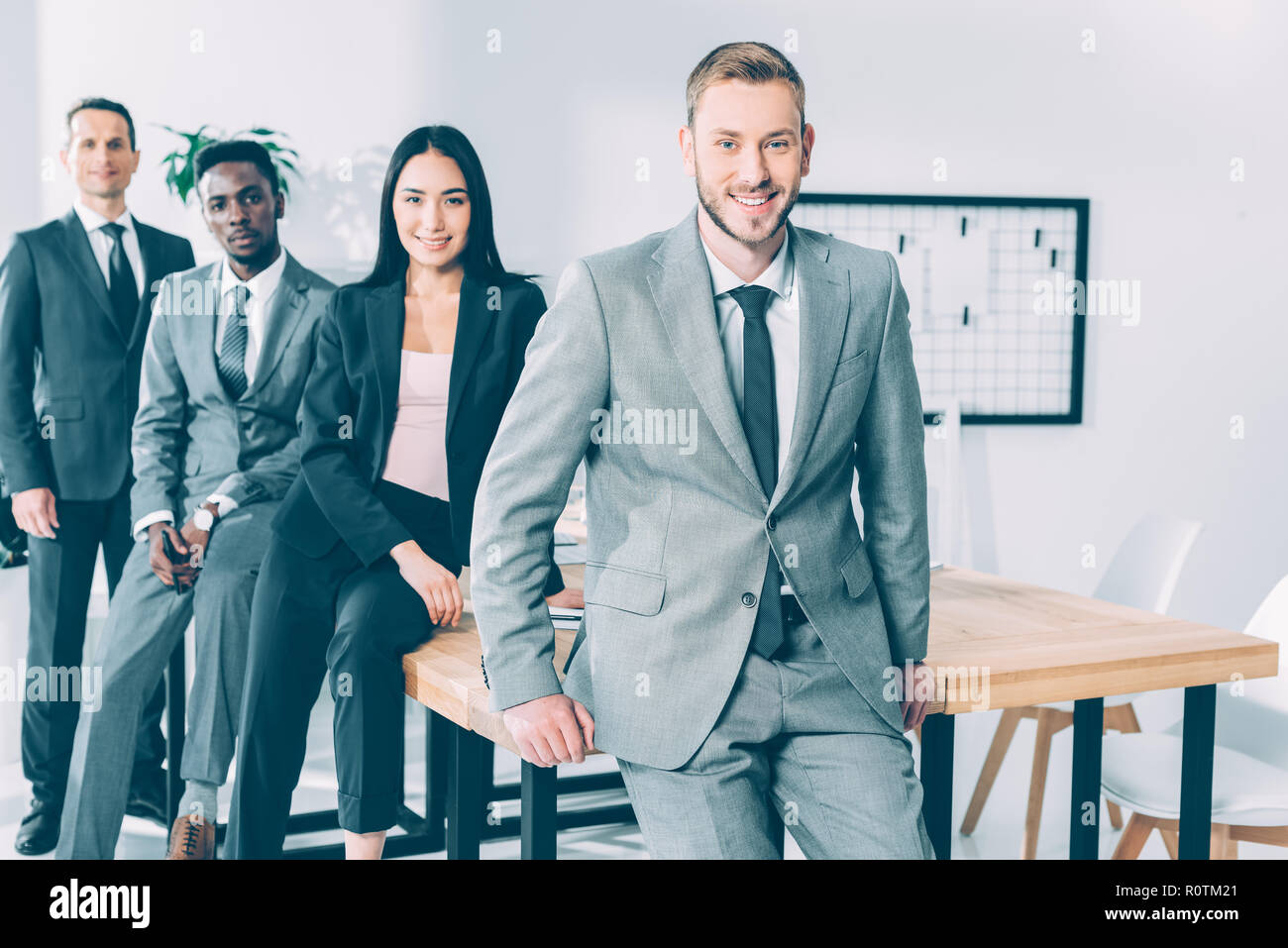 Heureux succès multicultural businesspeople sitting on table in office Banque D'Images