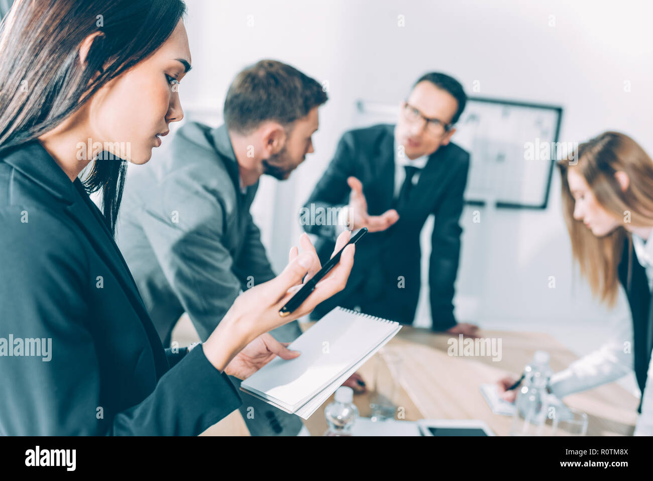 Young Asian businesswoman looking at portable lors de l'écoute de conversation Banque D'Images