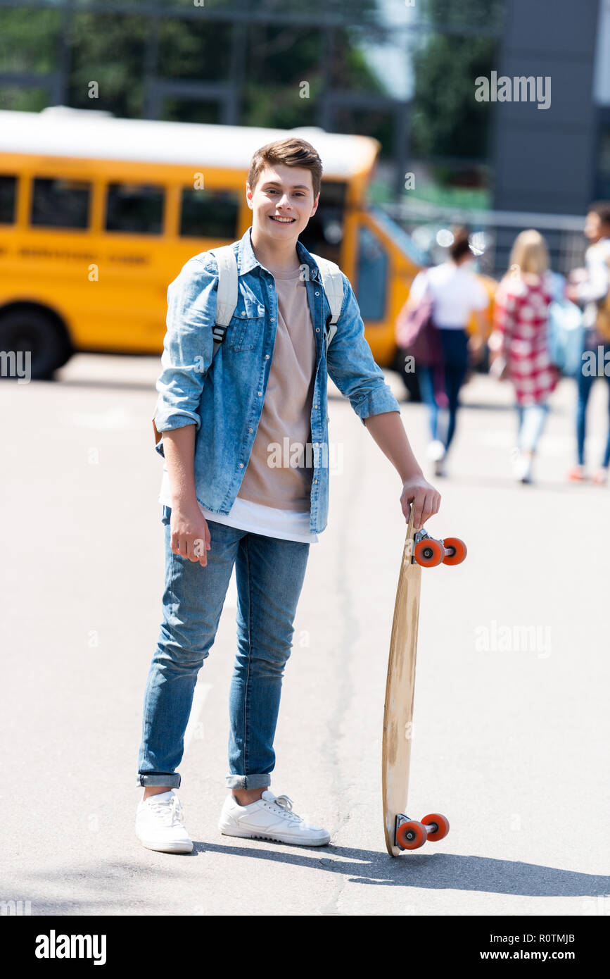 Happy teen écolière avec skateboard in front of school bus Photo Stock -  Alamy