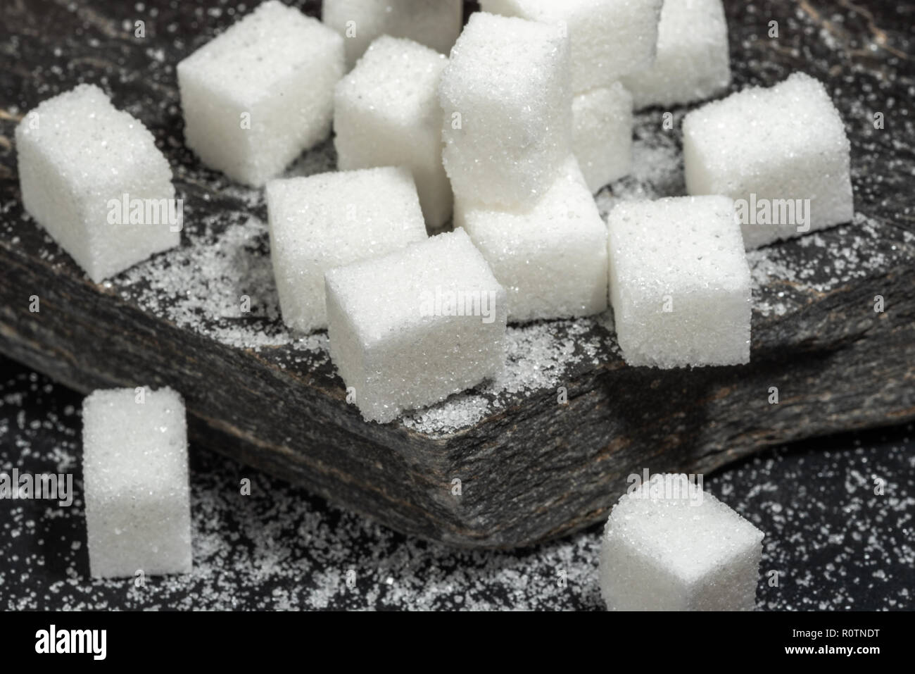Des morceaux de sucre et le sucre granulé sur slate black rock. Banque D'Images