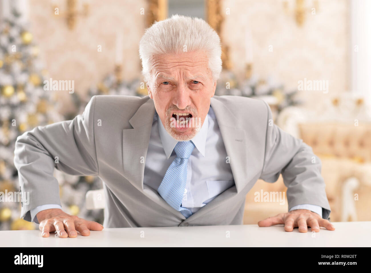 Close up portrait of senior businessman angry sitting at table Banque D'Images