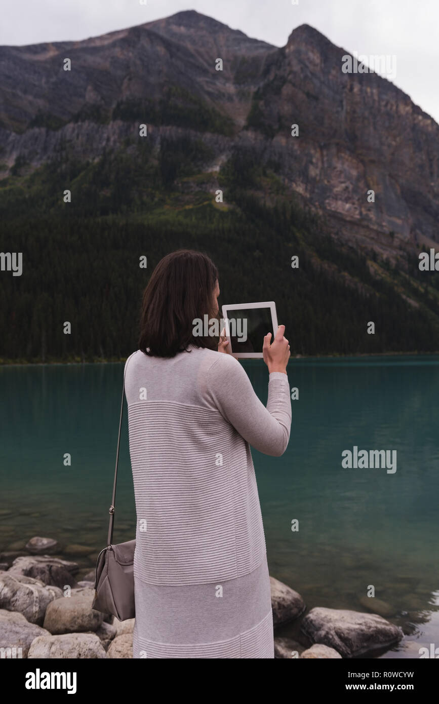 Femme en cliquant sur les photos avec tablette numérique près de lakeside Banque D'Images