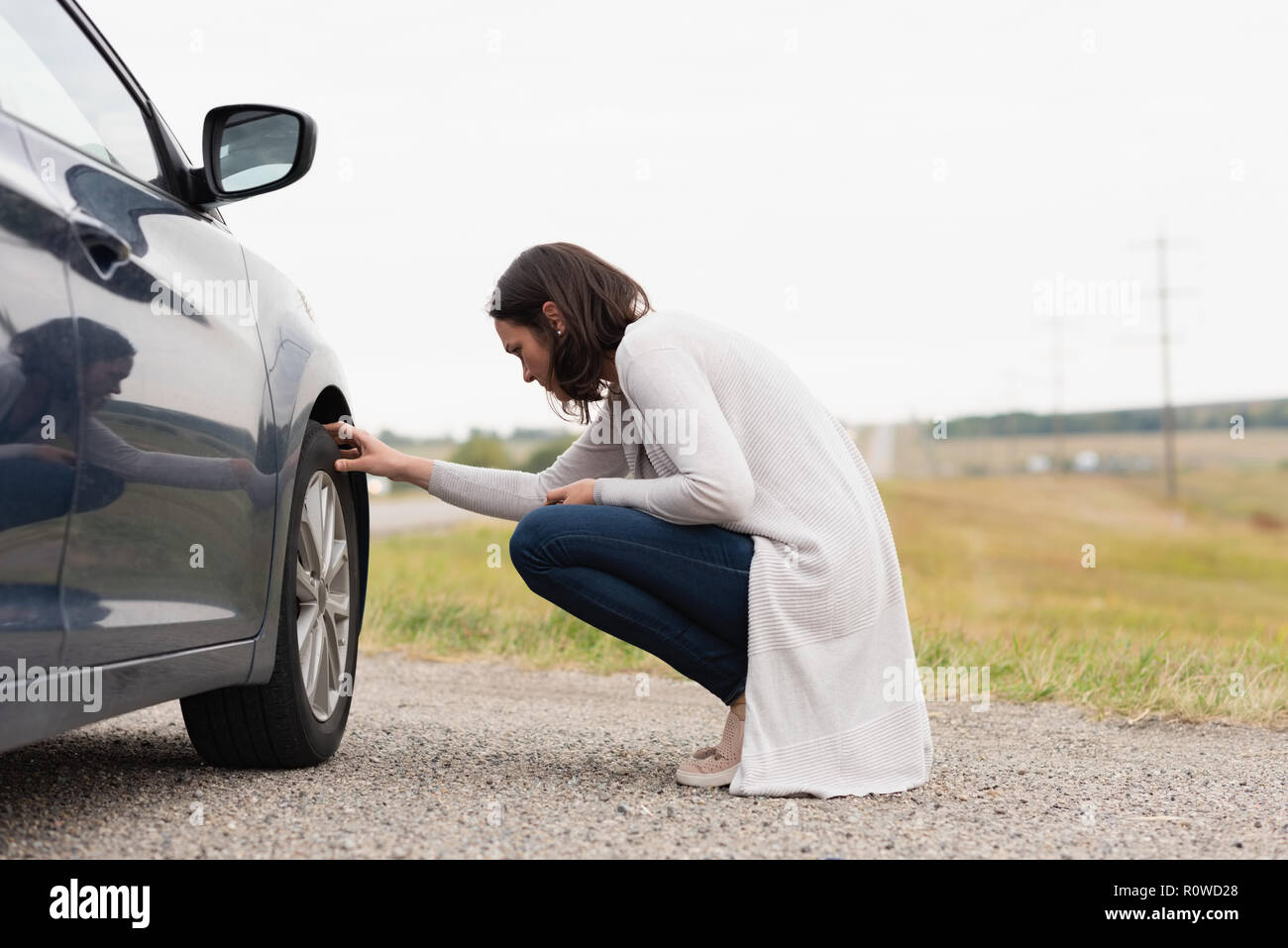 Femme contrôle de pneu de voiture au cours de ventilation Banque D'Images