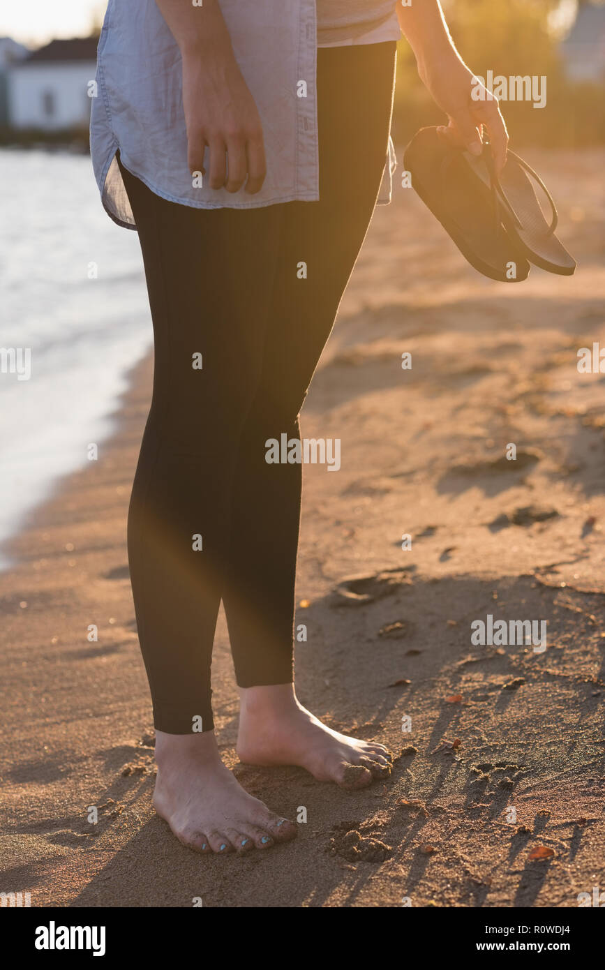Woman holding chaussons sur la plage Banque D'Images