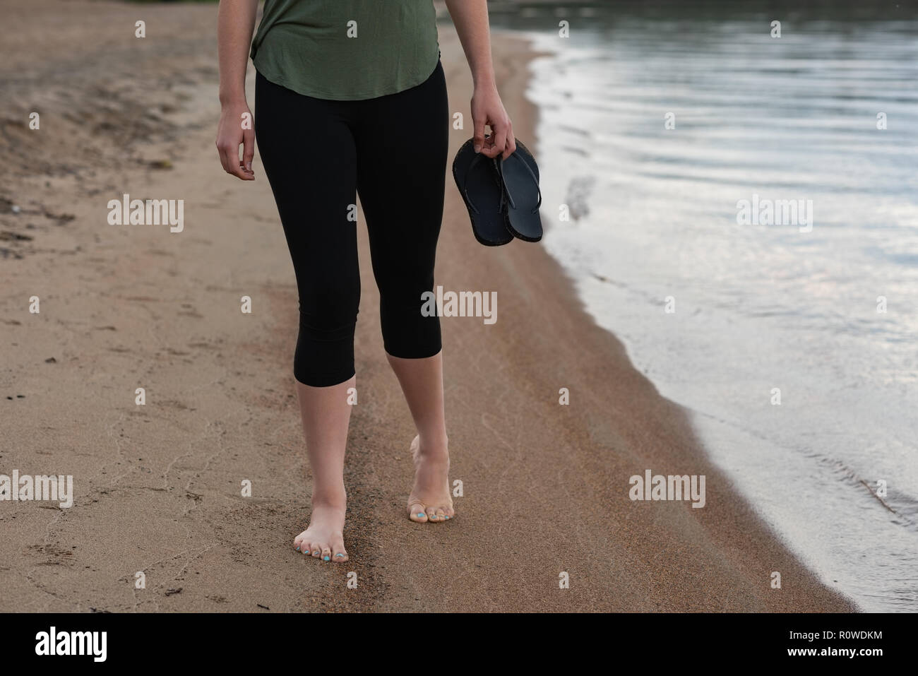 Woman holding chaussons sur la plage Banque D'Images