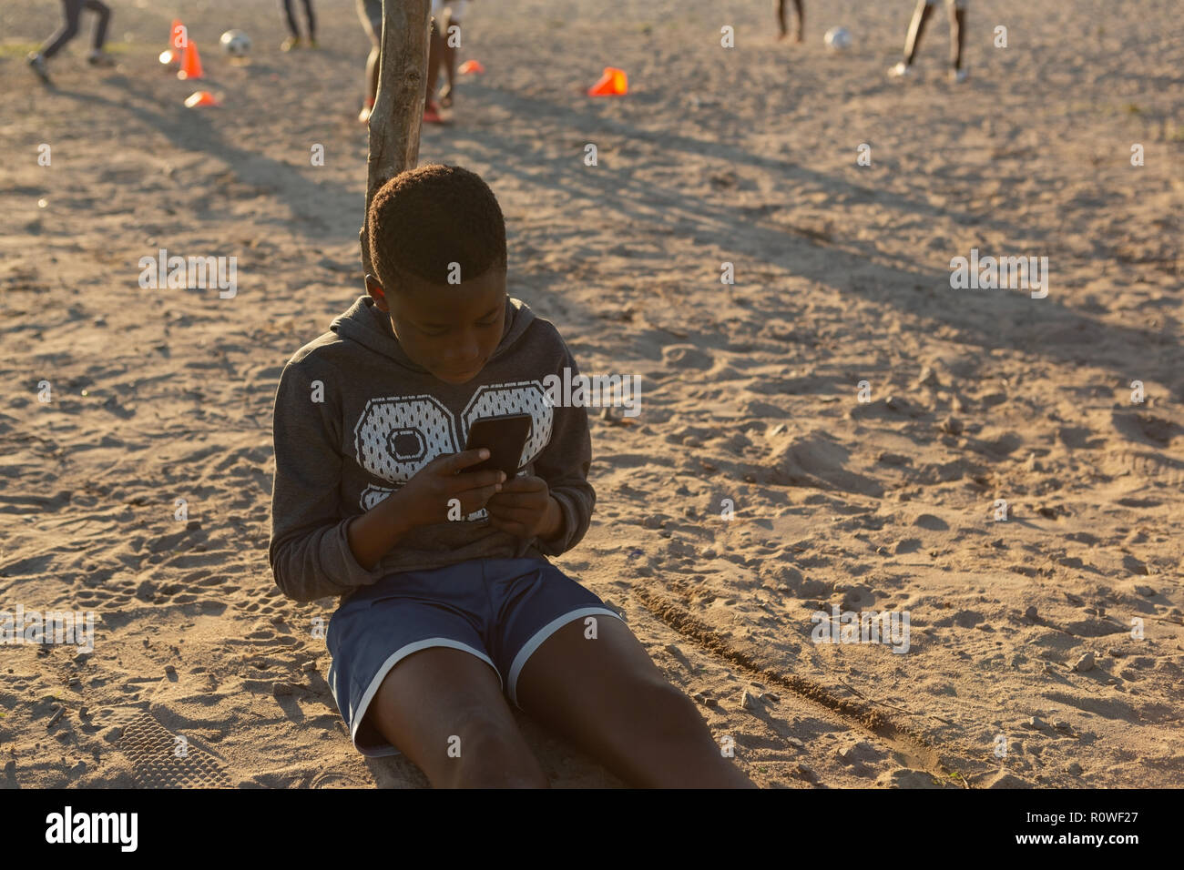 Kid à l'aide de téléphone mobile dans le sol Banque D'Images