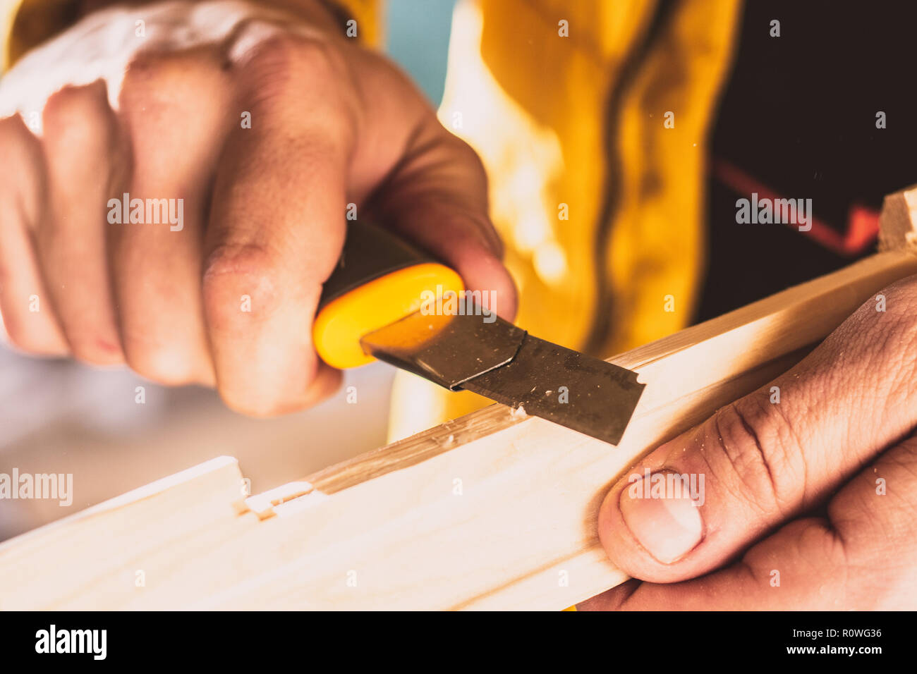La construction ou des travaux de réparation sur le bois. Close-up of man's hands tournant bloc en bois avec un couteau spécial. Tonique photo. Selective focus Banque D'Images