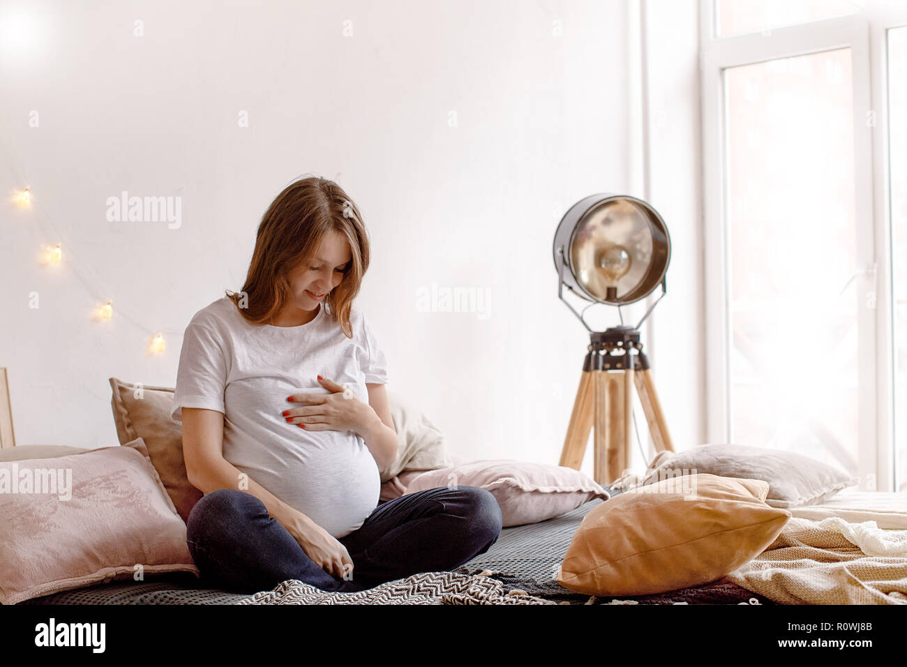 Pregnant woman sitting on bed Banque D'Images