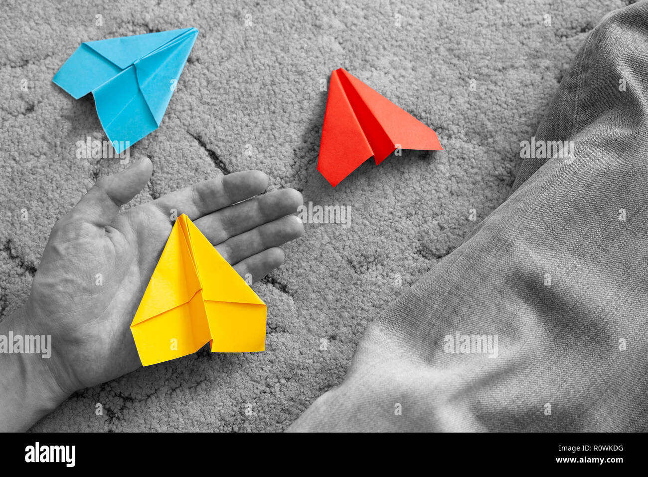 Perte de rêves. Personne est titulaire d'un avion en papier jaune dans sa paume ouverte avec plus d'espoir. Deux autres avions en papier sont couchées sur le sol. Banque D'Images