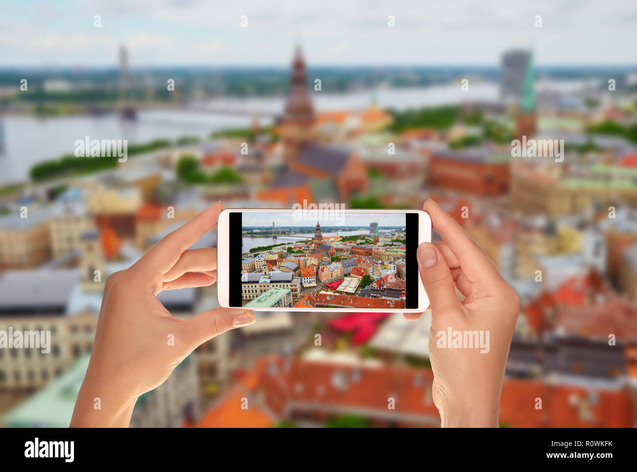 Un touriste prend une photo du panorama de la ville de Riga avec Tilt Shift lens sur un téléphone mobile Banque D'Images
