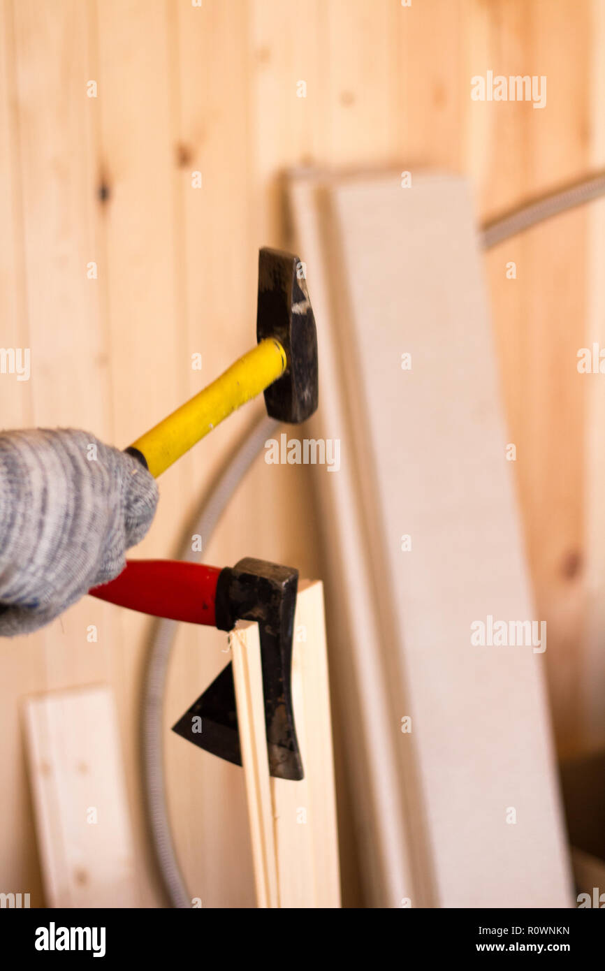 Création d'outils. Le travail du bois. Marteau jaune et rouge dans les mains des hommes en ax gants Banque D'Images