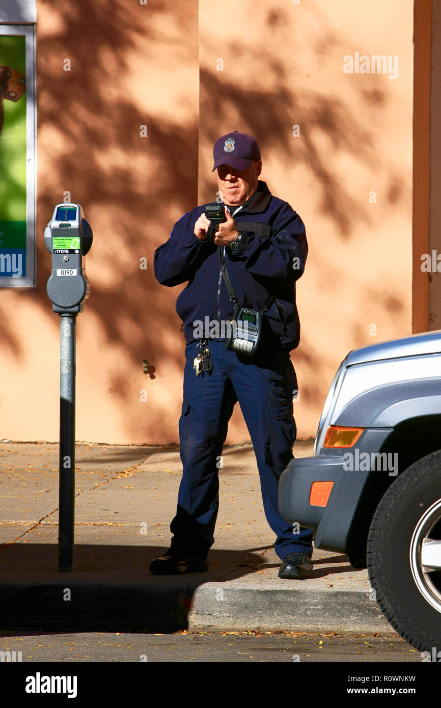 Un agent de l'homme gratuit écrit numériquement un ticket pour un véhicule dont le temps de stationnement au centre-ville d'elaspsed a Santa Fe NM, États-Unis Banque D'Images