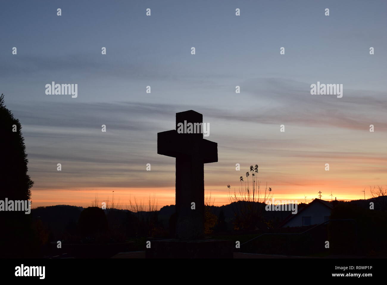 Chronologie de la soirée ciel crépuscule vu de derrière une croix en pierre de sable sculpture au cours de la coucher du soleil soleil dans le cimetière civil Reimsbach, Centre, Banque D'Images