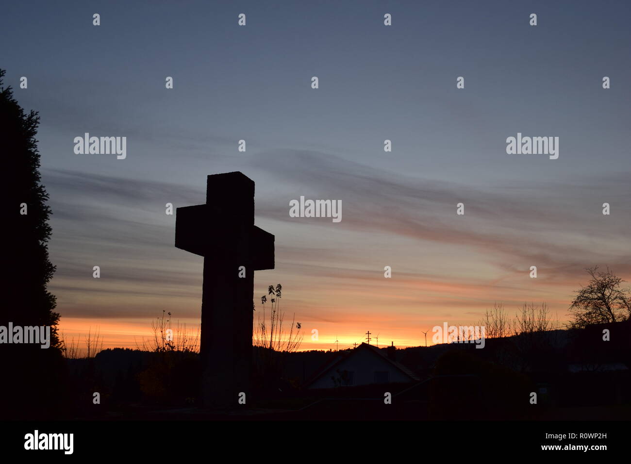 Chronologie de la soirée ciel crépuscule vu de derrière une croix en pierre de sable sculpture au cours de la coucher du soleil soleil dans le cimetière civil Reimsbach, Centre, Banque D'Images
